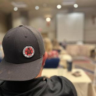 a hat on a person seen from behind while listening to a speaker