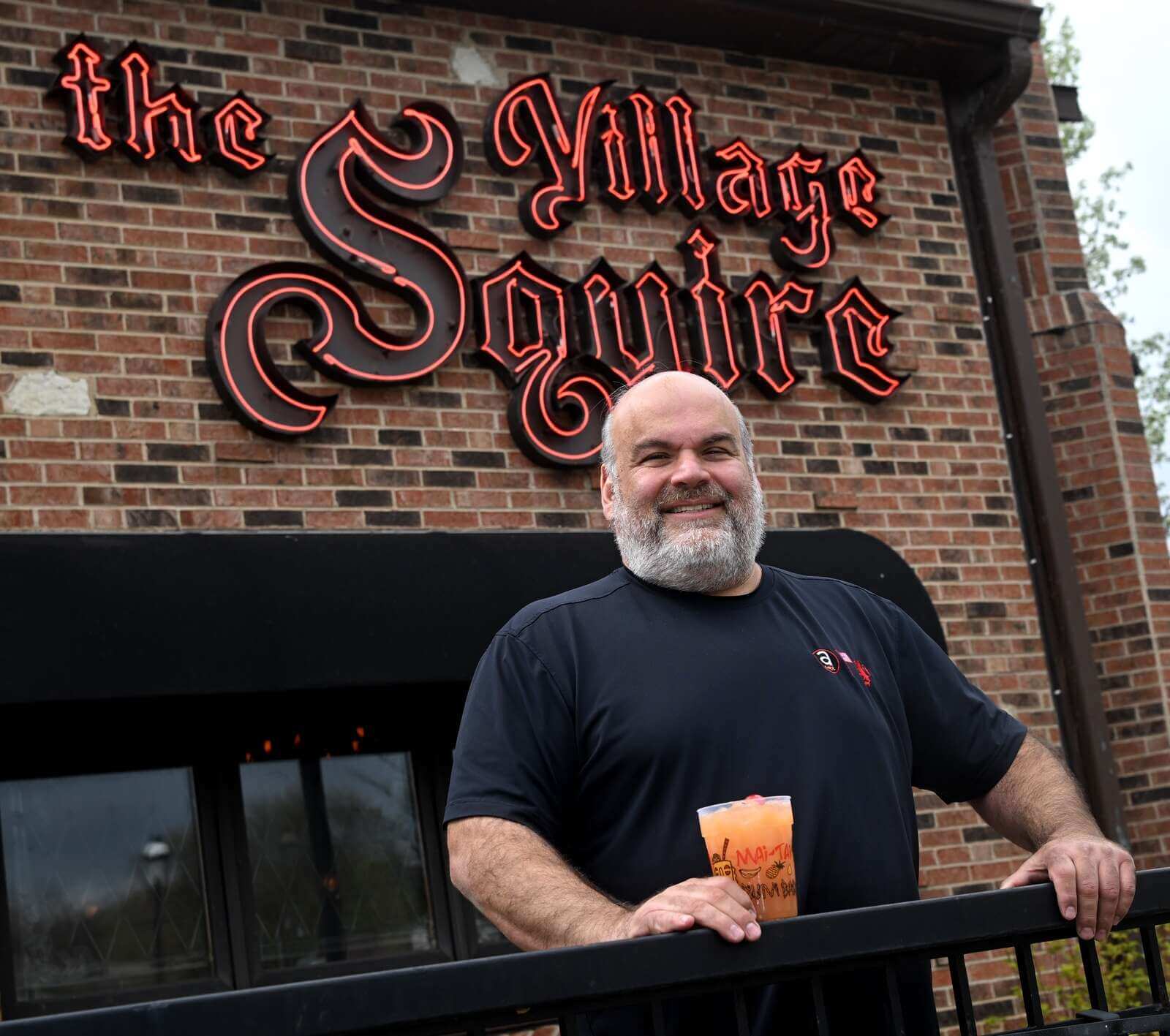 Bob Karas of the Karas restaurant groups holding a drink infront of the Village Squire