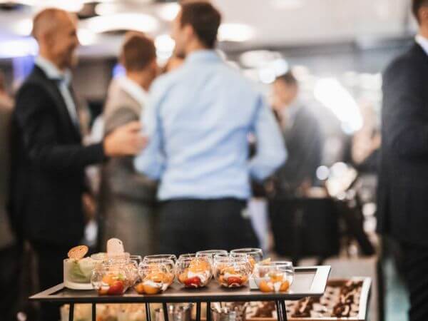 Business professionals networking at a reception event with appetizers displayed in the foreground.