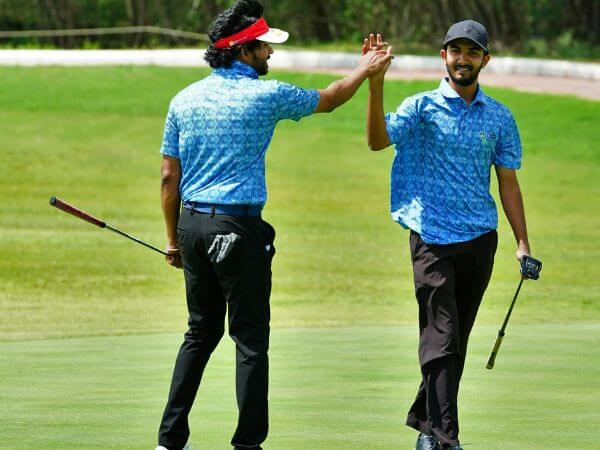 Two golfers celebrating with a high-five on the golf course during a business golf outing event.