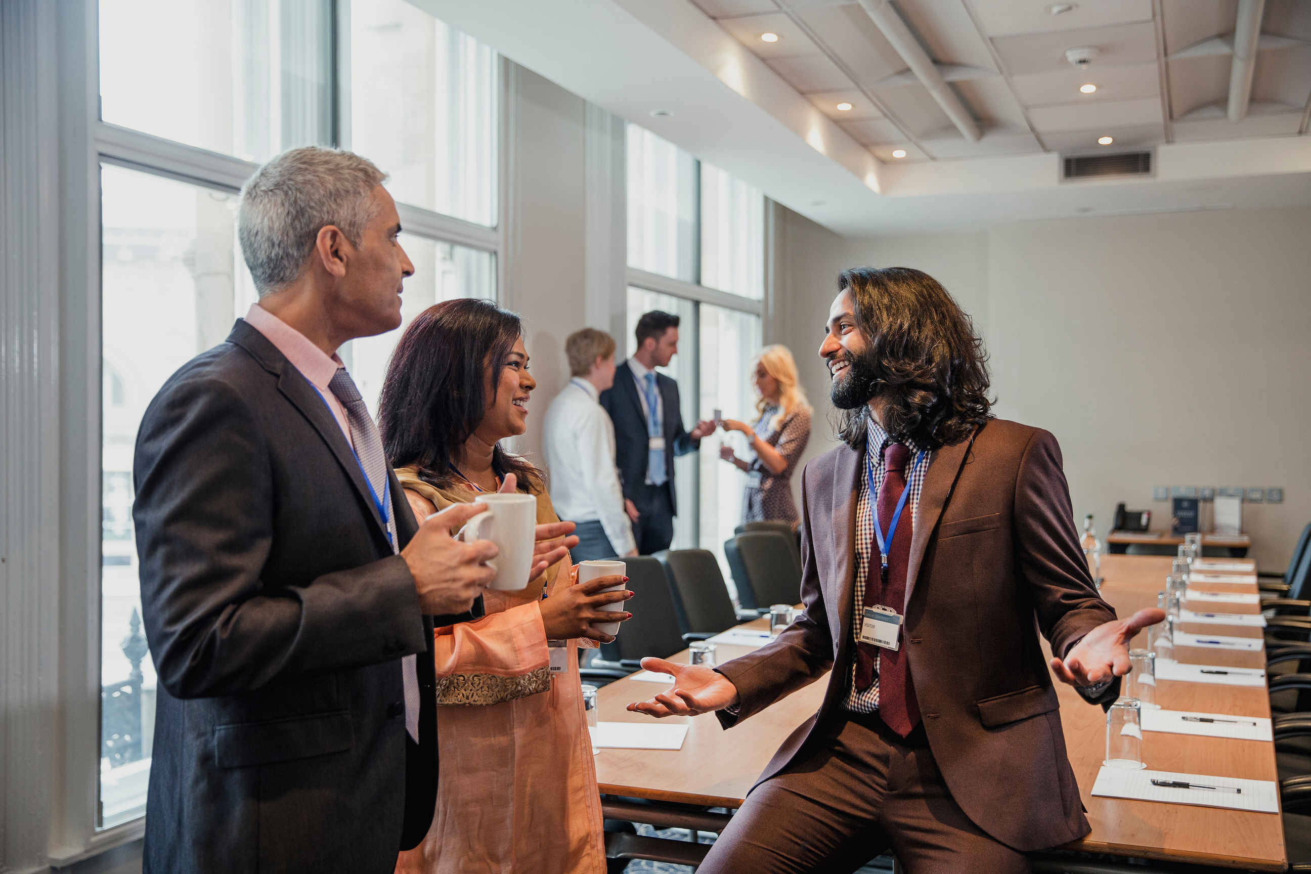 Small group of business men and women talking before a conference.