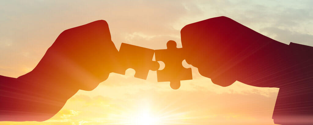 Business Teamwork, Join partnership and cooperation concept. Silhouette of two hands joining two pieces of puzzle connect together on morning sky.
