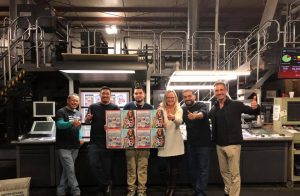 6 employees holding a page of the 2020 guide at printing facility