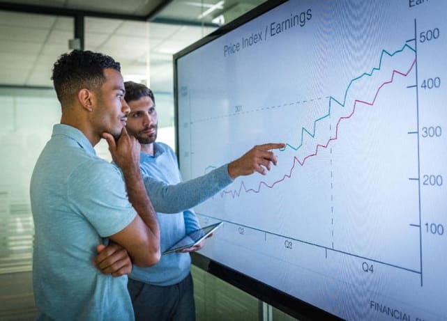 Two business people looking at charts on screen