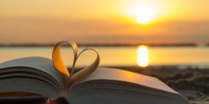 A book with pages in a heart shape in front of a lake at sunset.
