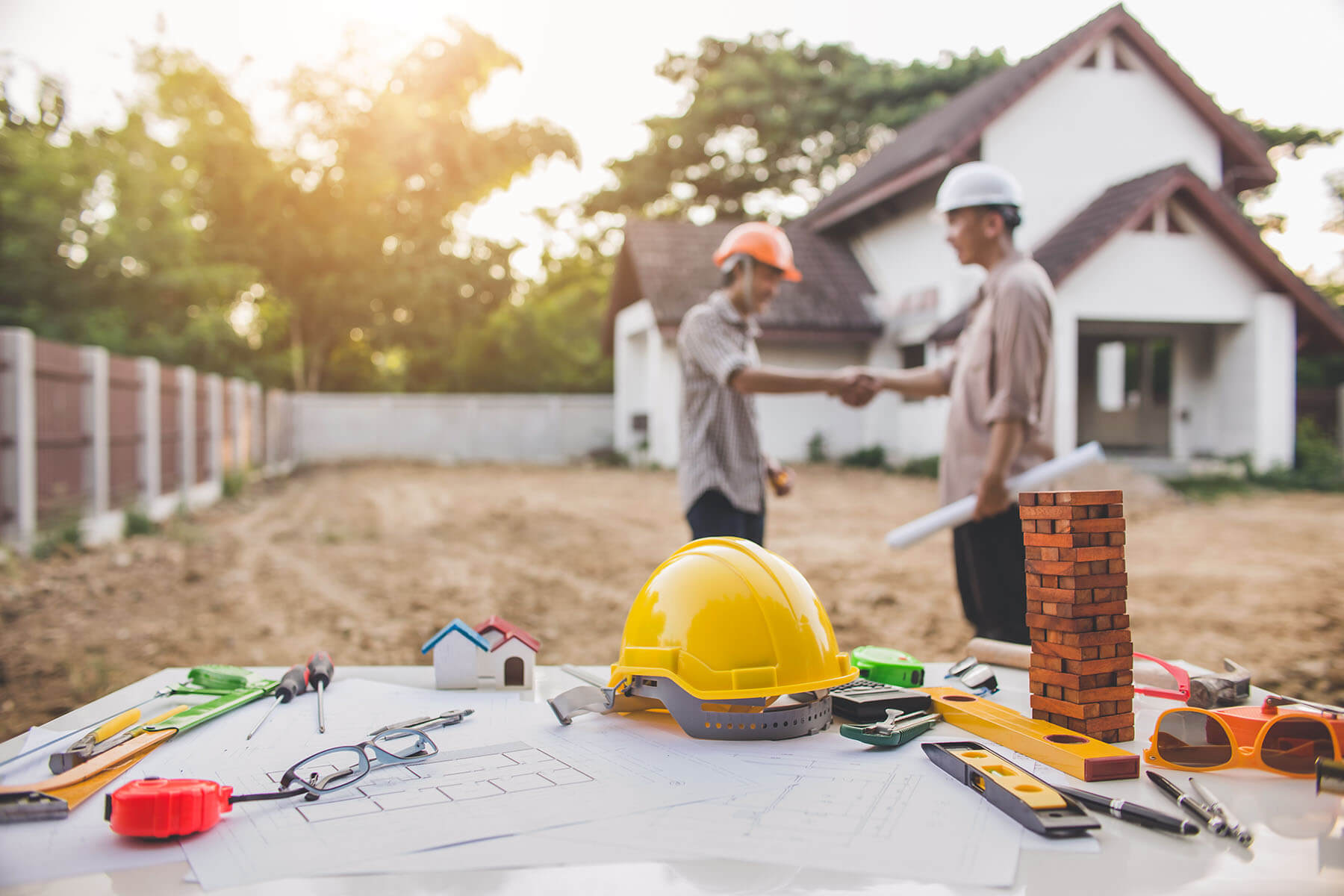 construciton plans on table 2 people shaking hands in the background