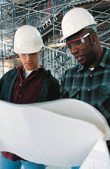two people in hard hats looking at blueprints
