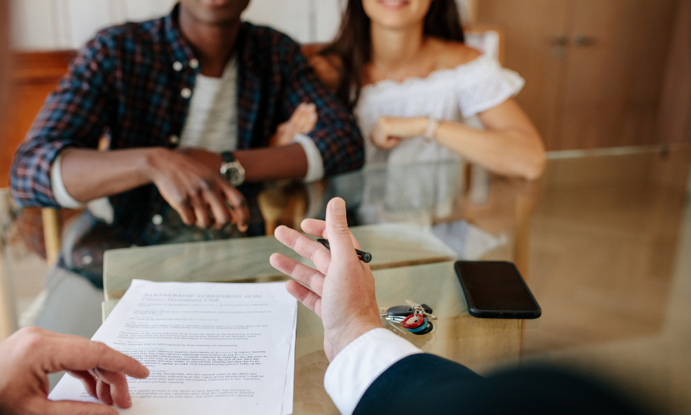 Home buyers at table with agent. House keys and contract on the table.