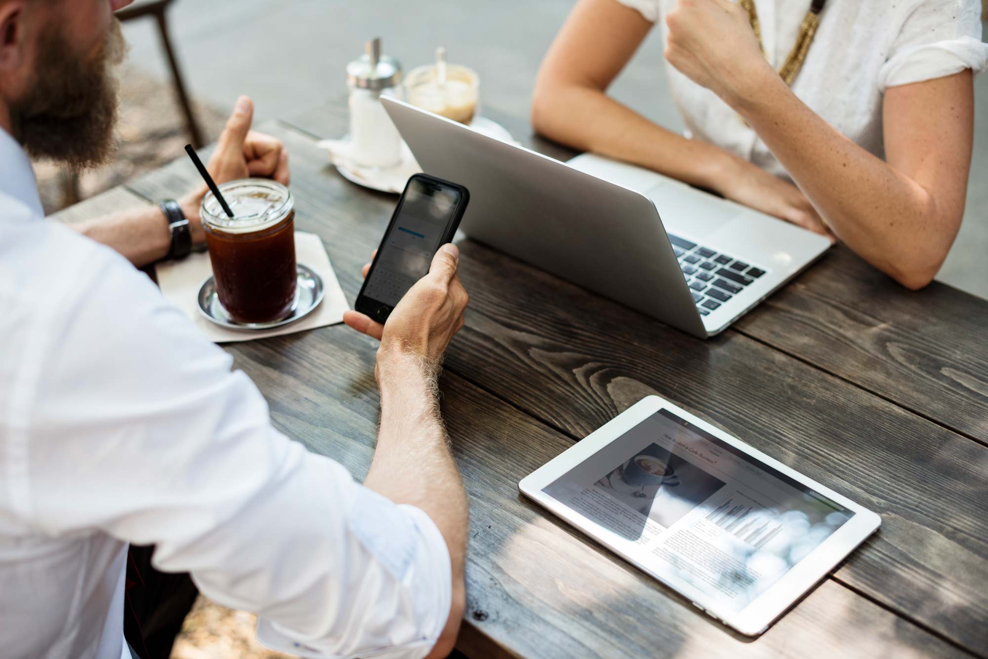 People at a Table with Laptop, Cell Phone, and Tablet