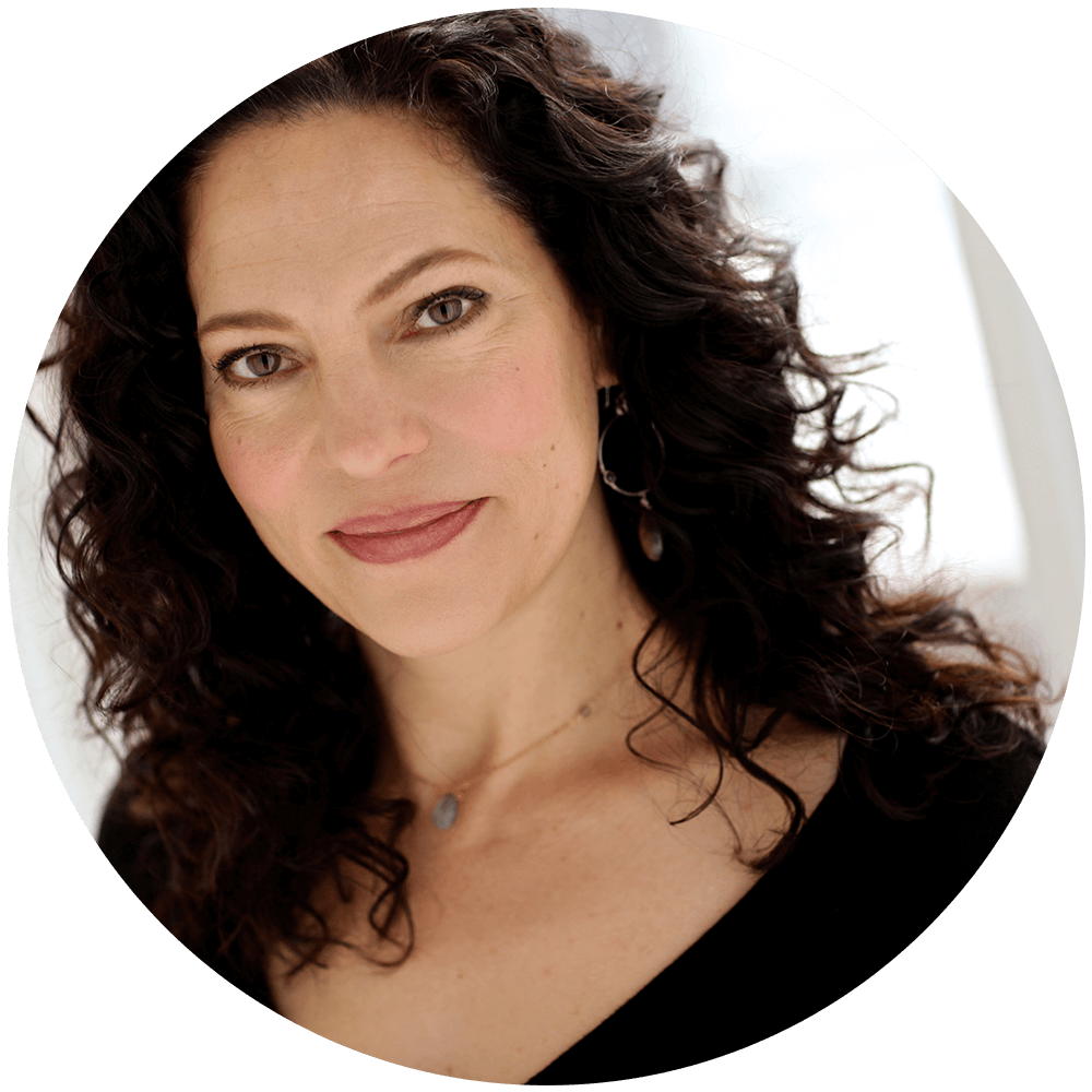 Giovanna is a white woman with brown curly hair posing in a sunny studio.