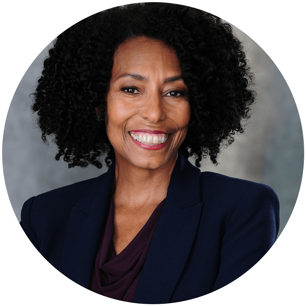 Black Female with caramel-colored skin and black curly hair, wearing a navy blazer and a purple blouse