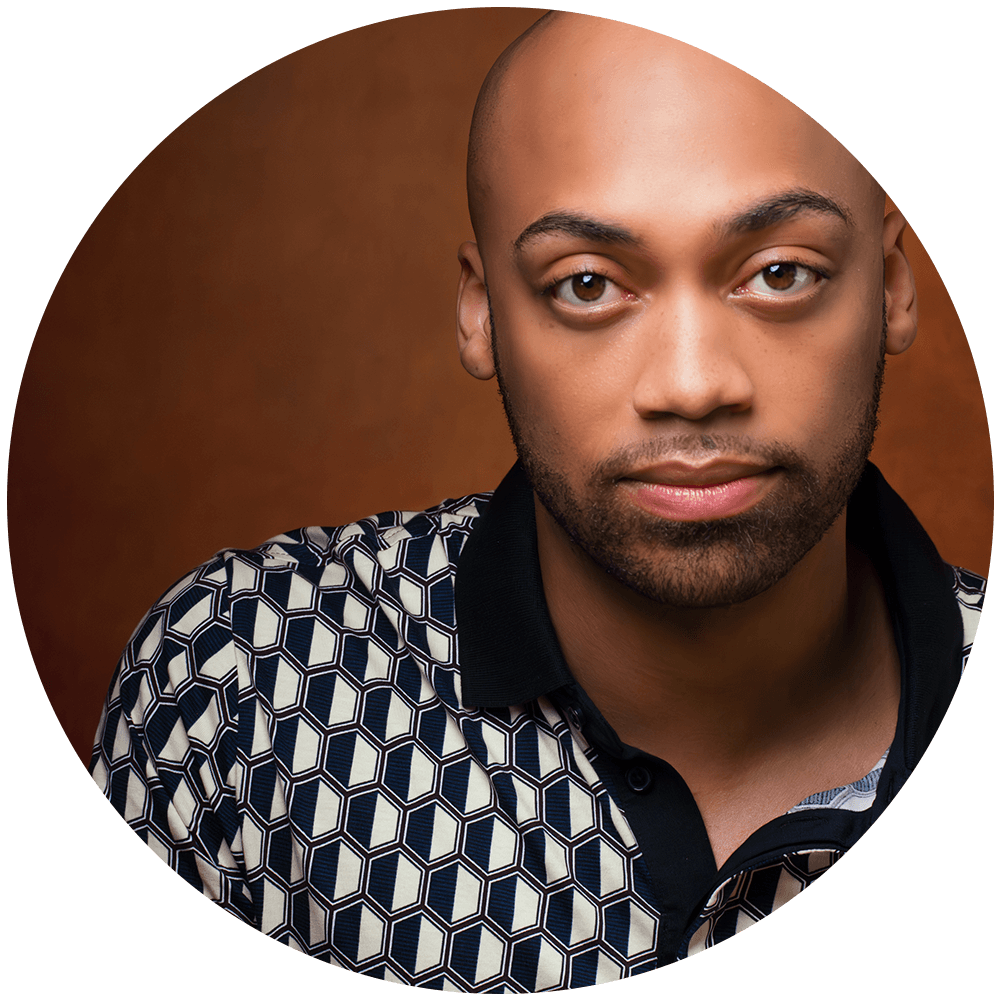 A professional headshot of Omar Stewart. featuring a close-up of their face with a brown background. They are wearing a white polo with a black collar and black geometric designs. His head is shaved bald.