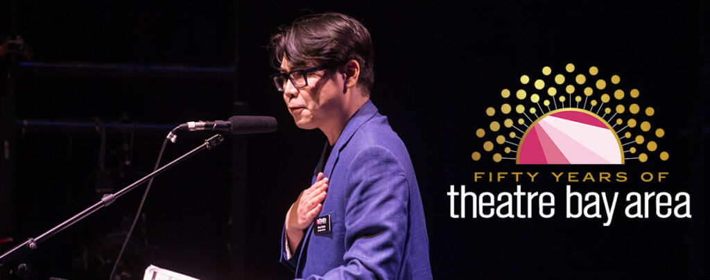 TBA Executive Director Sean Fenton speaks at a microphone with his hand over his heart. There is a TBA 50th Anniversary Logo on top of the picture