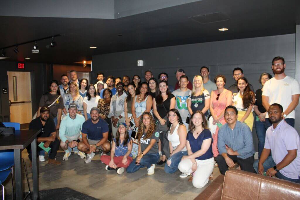 Large group of people posing for a picture agains a wall