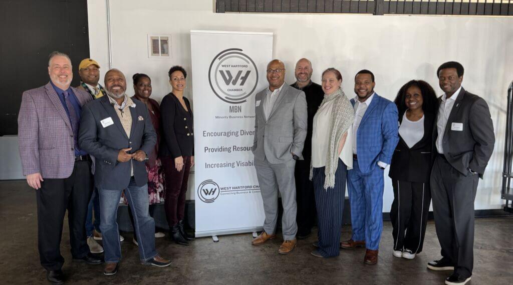 Group of people posing inf ront of a sign.