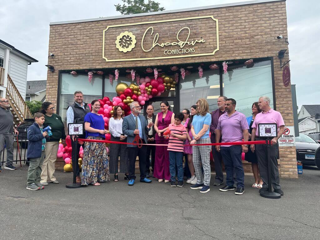 Group of people doing a ribbon cutting outside of a brick building